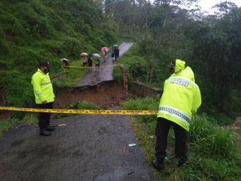Petugas kepolisian memasang garis polisi di sekitar jembatan yang putus.