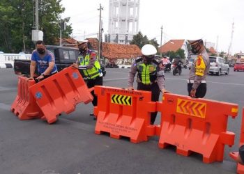 Sejumlah petugas tengah memasang alat penyekat di salah satu ruas jalan.